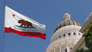 The dome of the California State Capitol building with the flag of California. The Sexual Violence Prevention Association (SVPA) urges California to prevent state sexual violence. A years-long investigation found that sexual violence was widespread and unmitigated in Califonia prisons. Elected officials must take action. The SVPA is demanding the California prison system significantly improve prevention measures. We are also endorsing two bills, AB 464 and SB 337.